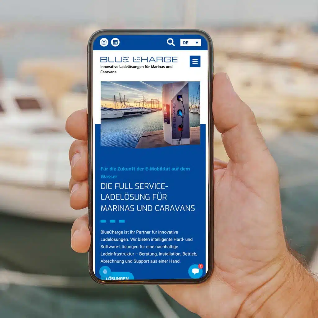 Hand hält Smartphone mit E-Ladelösungen-Website