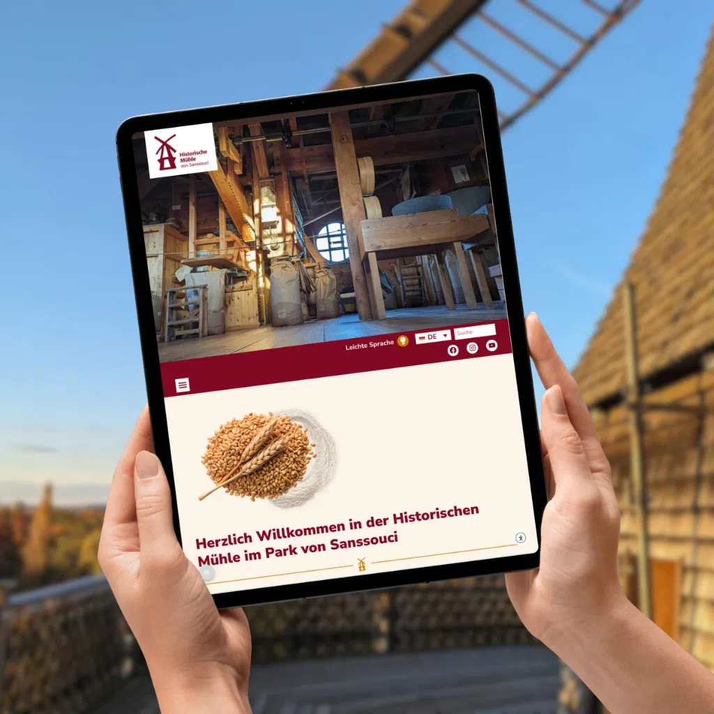 Tablet mit Mühlen-Website in der Hand.