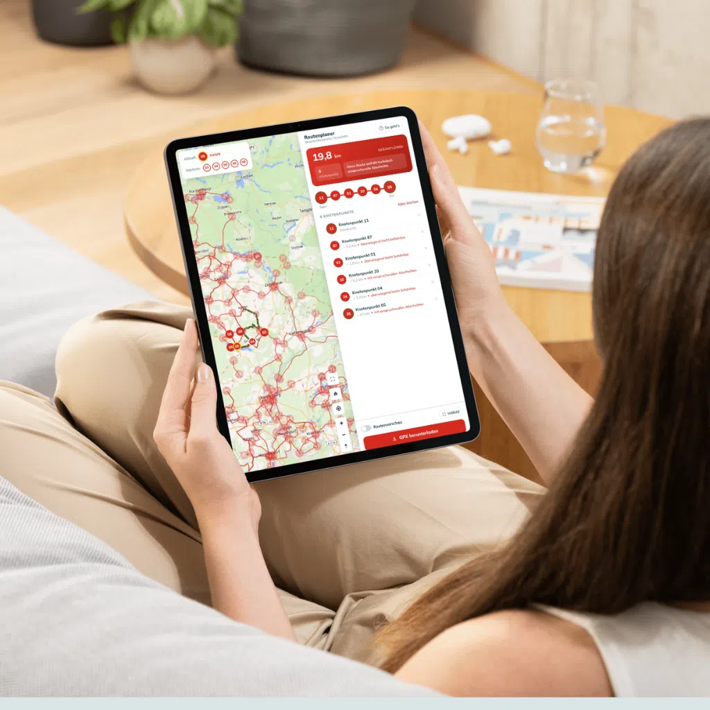 Frau nutzt Tablet mit Routenplaner auf Sofa